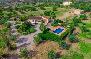Una villa con piscina, rodeada de exuberante vegetación y montañas al fondo.