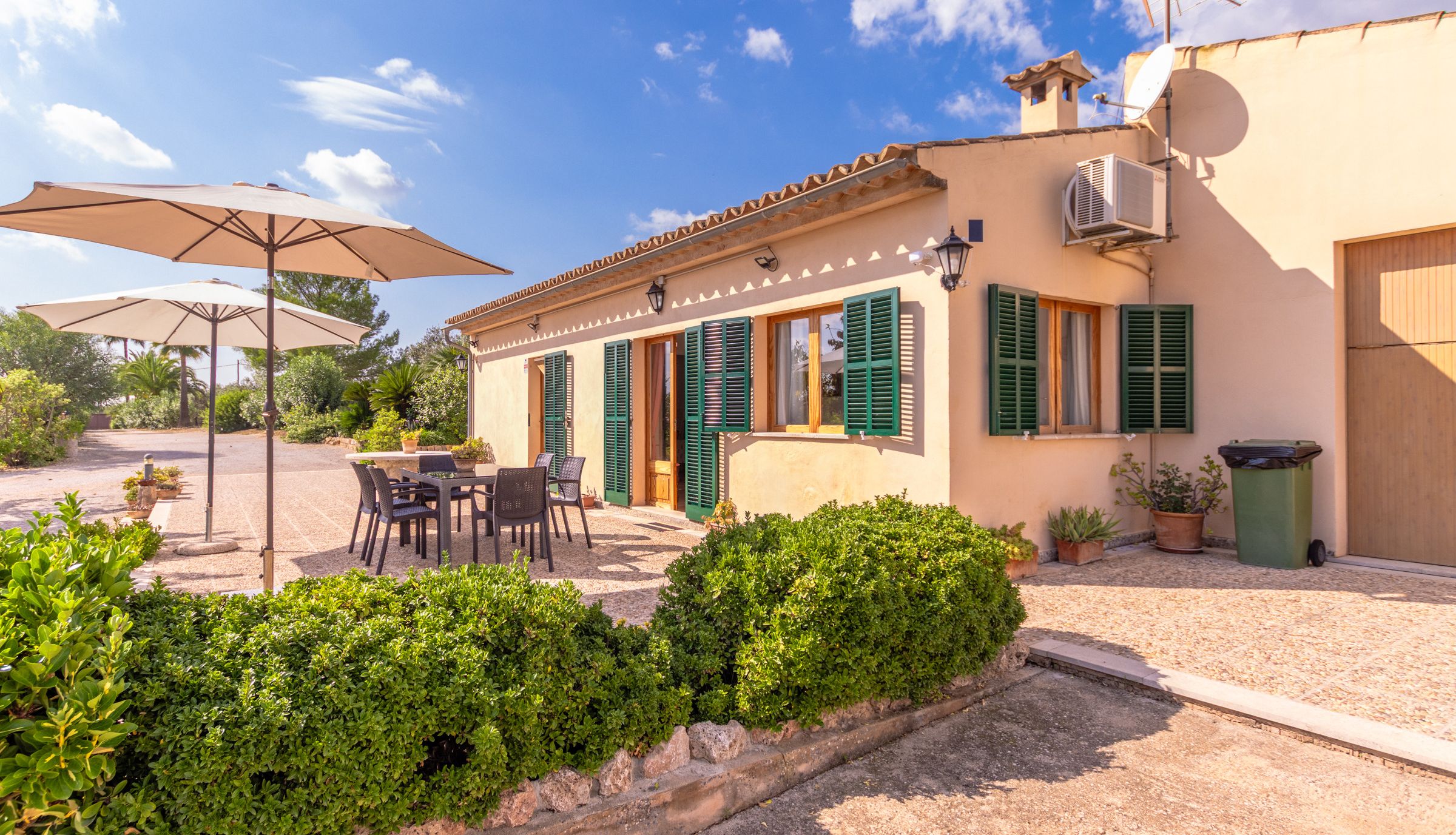 Una villa con mobiliario de exterior, antena parabólica y jardín bien cuidado.
