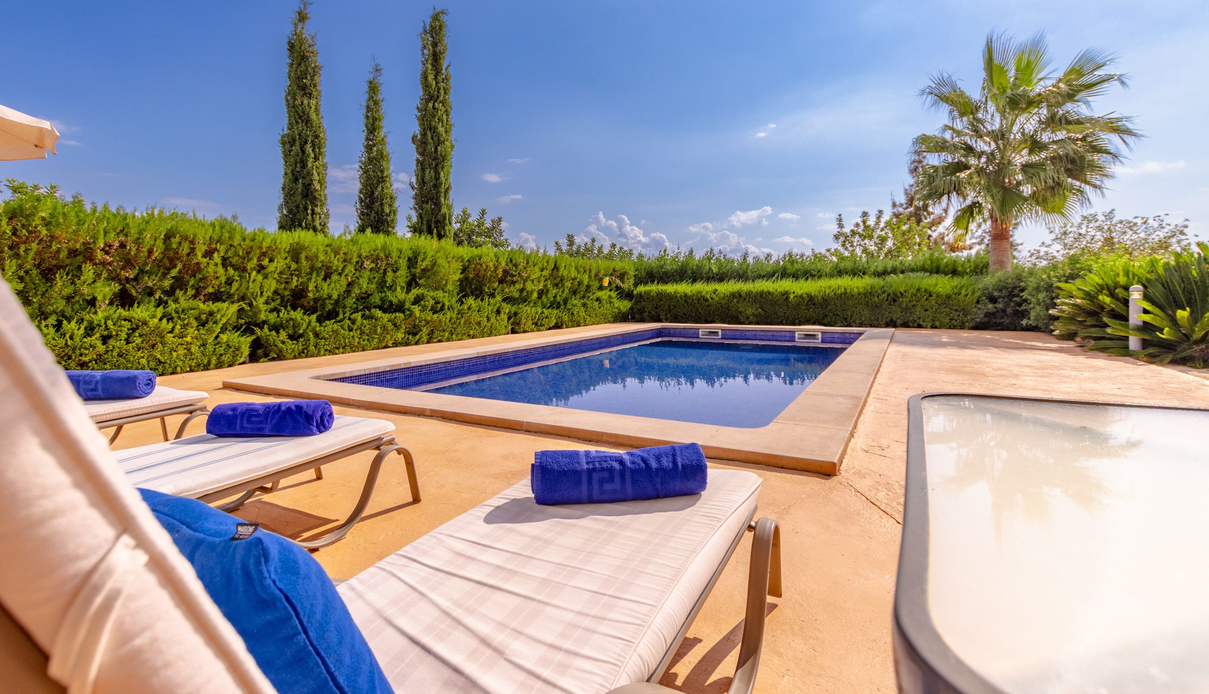 A poolside area with lounge chairs, a hot tub, and a clear view of the sky.