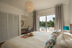 Ein Schlafzimmer mit einem großen Bett, einem Schreibtisch, einem Stuhl und Blick auf einen Swimmingpool.