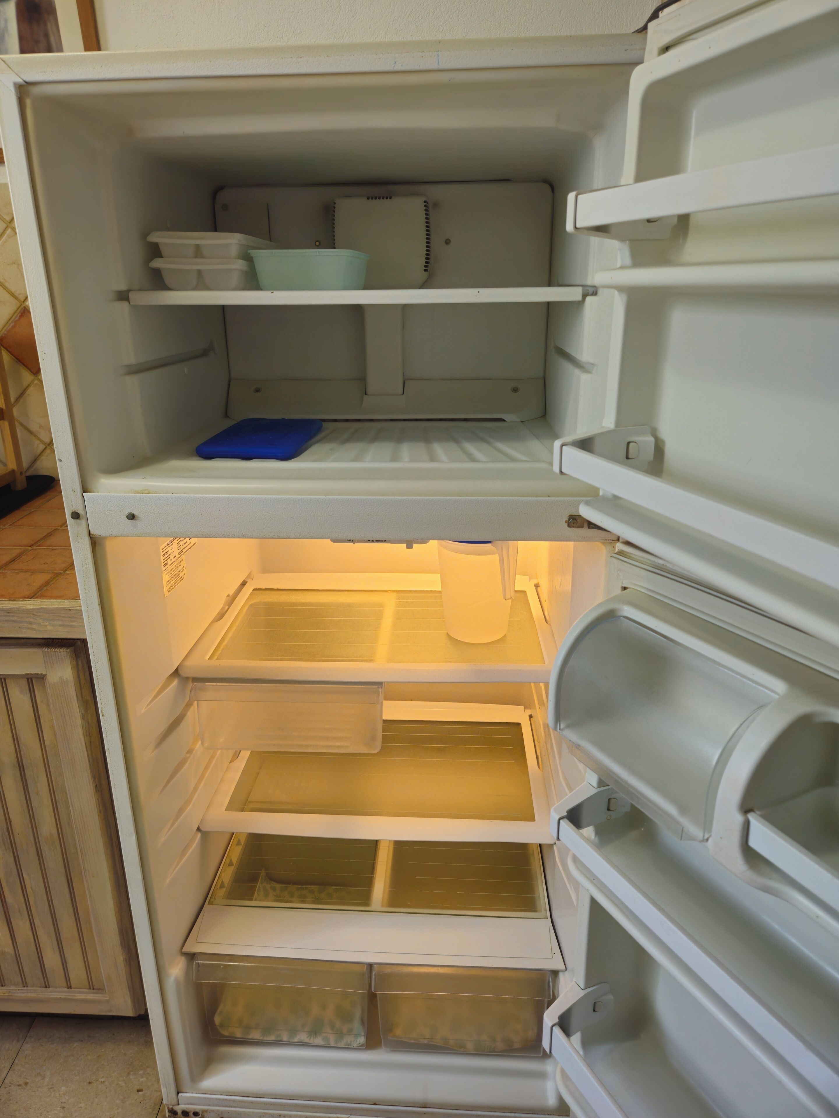 Un refrigerador abierto con varios estantes y cajones, algunos de ellos con objetos en su interior.