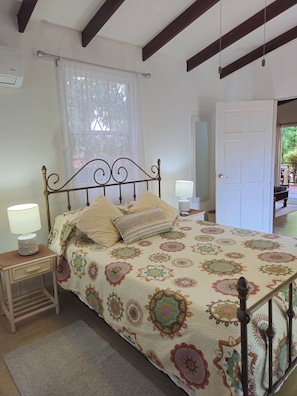 Une chambre à coucher avec un lit, des lampes de chevet, une table de chevet, une porte et une fenêtre avec des rideaux.