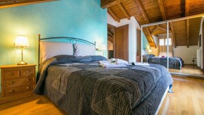 A bedroom with a bed, wooden dresser, and a mirror reflecting the room.