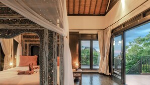 A bedroom with a canopy bed, a large window with curtains, and a view of greenery outside.