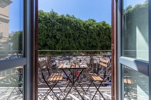 A balcony with outdoor seating, a metal railing, and a view of a green hedge. - Domus Sicily - Loft Piazza Marina - Palermo (Palermo)