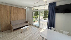 Een moderne kamer met een houten garderobe, een grijze bank, een klein tafeltje en een plafondventilator.