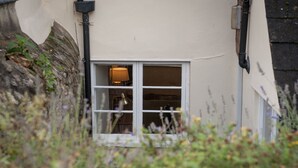 A window with a lamp inside, surrounded by greenery. - Lavender Cottage - sleeps 4 guests  in 2 bedrooms (Lyme Regis)