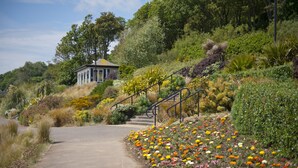 A pathway leading to a gazebo surrounded by diverse vegetation and colorful flowers. - Lavender Cottage - sleeps 4 guests  in 2 bedrooms (Lyme Regis)