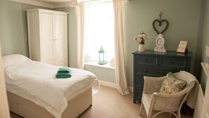 A bedroom with a bed, a dresser, a chair, and a window with curtains. - Lavender Cottage - sleeps 4 guests  in 2 bedrooms (Lyme Regis)