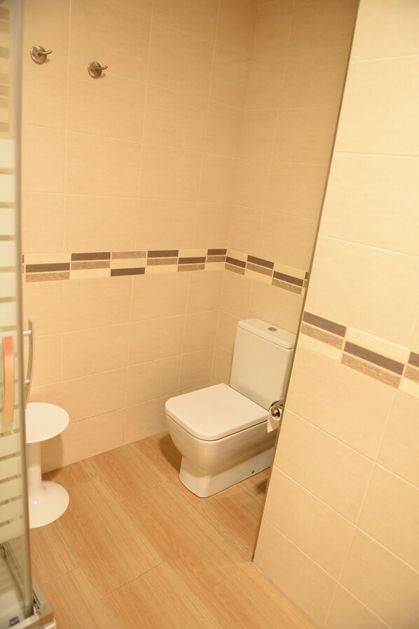 Ein kleines, sauberes Badezimmer mit Toilette, Waschbecken und Duschkabine.