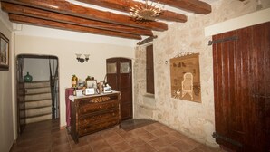 Une pièce rustique avec des poutres apparentes, un mur en pierre, une commode en bois et une grande porte en bois.