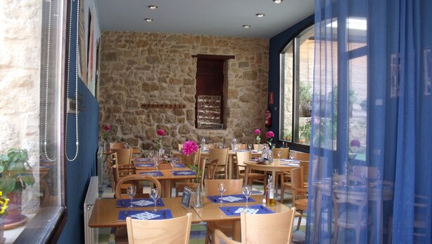 Un restaurant aux murs de pierre, aux tables et aux chaises en bois.
