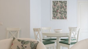 A dining area with a white table and chairs, a cactus-patterned pillow on a sofa, and a framed cactus artwork on the wall. - Among magnolias, in the heart of the city ... (Córdoba)