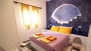 Ein Schlafzimmer mit einem Bett, einem Nachttisch, einem Fenster mit Vorhängen und einem Wandgemälde.