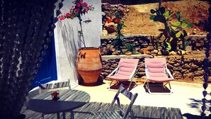 Eine Terrasse mit zwei Liegestühlen, einem Tisch und einem großen Terrakottatopf.