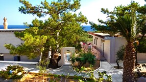 Ein Küstenanwesen mit Garten, einem kleinen Gebäude und Meerblick.