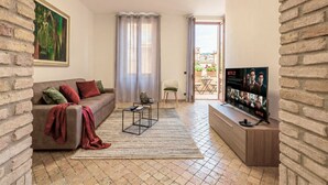 Ein Wohnzimmer mit einer Couch, einem Couchtisch, einem Fernseher und Blick ins Freie.