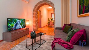 Ein Wohnzimmer mit Fernseher, einer Couch, einem Couchtisch und einem Kamin.