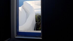 A view through a window of white terraced structures overlooking a body of water and distant mountains.