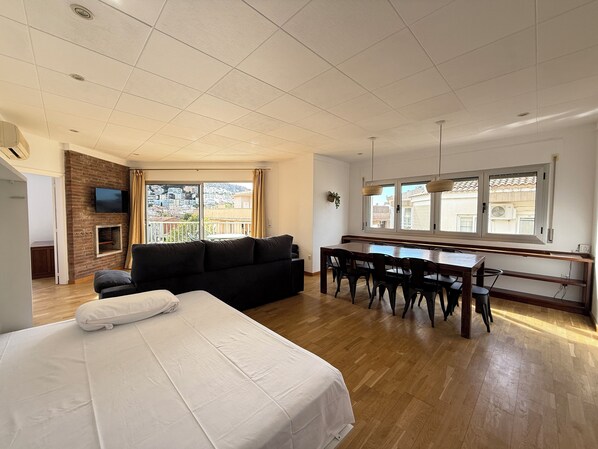 A spacious room with a large bed, a sofa, a dining table with chairs, a fireplace, and a TV mounted on the wall. - Agi Peater 3A Apartamento for rent in Roses Girona. (Roses)