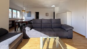 A modern living room with a grey sofa, wooden coffee table, and a dining area with a wooden table and chairs. - Agi Peater 3A Apartamento for rent in Roses Girona. (Roses)