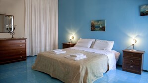 A bedroom with a bed, two nightstands, a dresser, and a painting on the wall. - VILLA BUONASERA ON THE SEA (Santa Flavia)