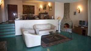 A living room with a stone fireplace, a sofa, a coffee table, and a television. - VILLA BUONASERA ON THE SEA (Santa Flavia)