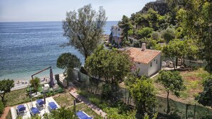 A coastal property with a view of the sea, a fenced garden, and a small building with a tiled roof. - VILLA BUONASERA ON THE SEA (Santa Flavia)