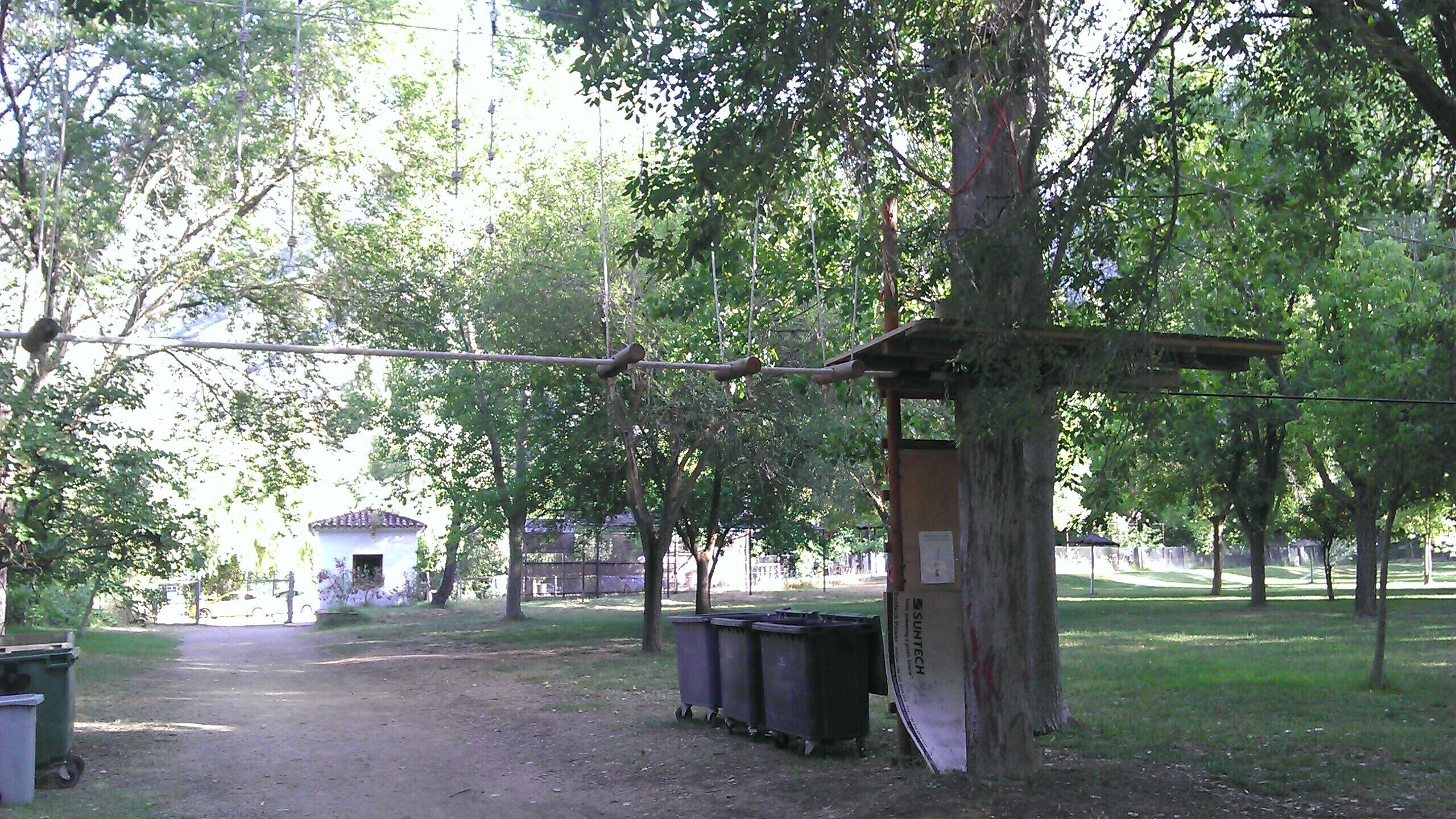 Un parc doté d’une structure en bois, d’un sentier et de poubelles.