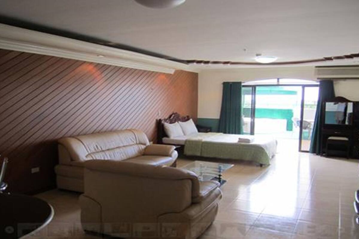 Habitación de hotel con sofá, cama, televisión y vistas al exterior.