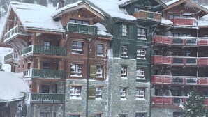 Un immeuble à plusieurs étages, doté de balcons et de fenêtres, entouré de neige.