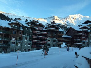 A snow-covered mountain lodge with multiple balconies and a ski slope in the background. - Arc 1950, Large 1 BR overlooks the "jardin de neige", youngest kids' ski school (Bourg-Saint-Maurice)