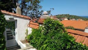 Un barrio residencial con tejados de terracota, una esfera de piedra en la cima de un edificio, y una vista despejada del mar.