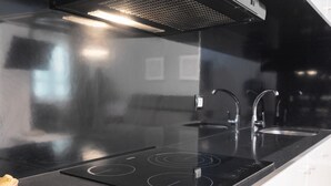 A modern kitchen with a black countertop, stainless steel appliances, and a range hood.