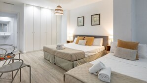 A hotel room with a bed, a chair, a wardrobe, and a hanging light fixture.