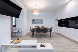 Une cuisine moderne avec des meubles blancs, un plan de travail noir et un coin repas comprenant une table et des chaises.