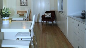 Une cuisine moderne avec des meubles blancs, un coin repas avec des chaises blanches et un plancher en bois.
