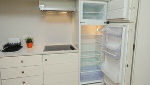 Une cuisine équipée d’un réfrigérateur encastré, d’une cuisinière et d’un plan de travail agrémenté d’une plante en pot.