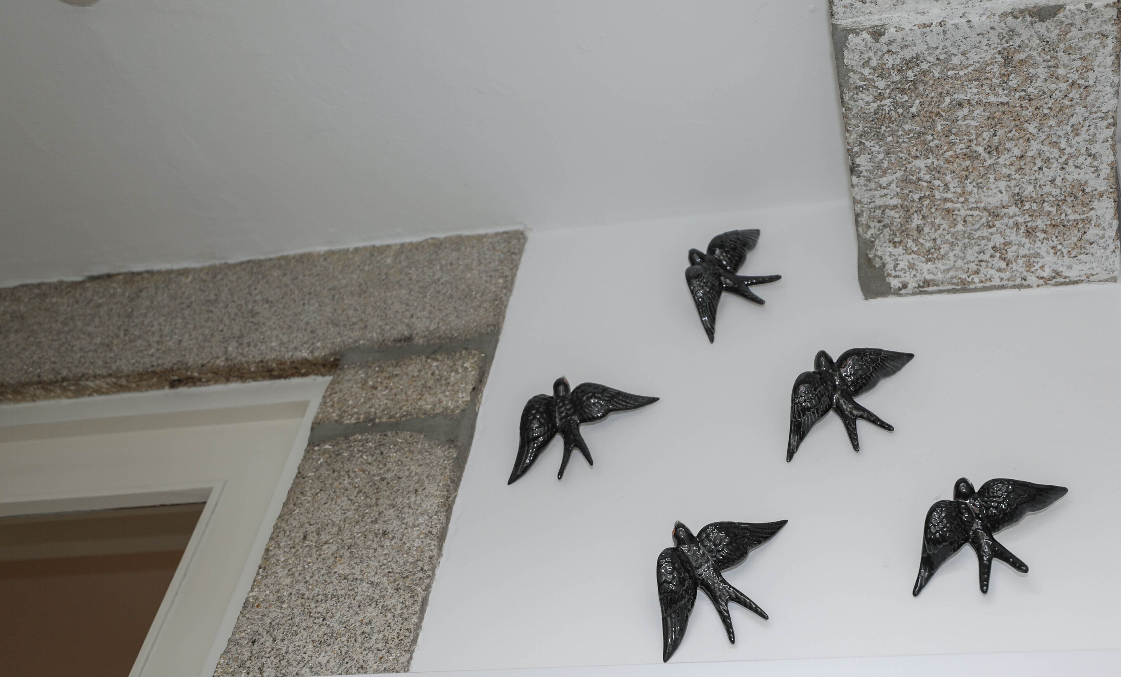 A wall with five black bird-shaped wall art pieces.