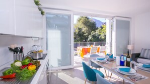 A modern kitchen with a dining area, a balcony with outdoor seating, and a view of trees and mountains. - Casa Laura Apt. 6, Plesio, Italy (Plesio)