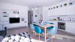 A modern kitchen with white cabinets, a built-in oven, and a dining area with blue chairs. - Casa Laura Apt. 6, Plesio, Italy (Plesio)