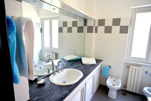 Een bad/douchecombinatie, een haardroger, een bidet, handdoeken