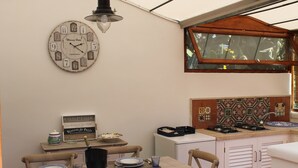 Ein Essbereich mit einer Uhr, Tisch gedeckt mit Tellern und Besteck, und einem Fenster mit Blick auf Grünflächen.