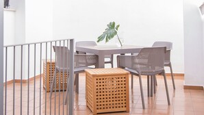 Eine Terrasse mit einem runden Tisch, vier Stühlen, einem Topfpflanzen und einer Holzkiste.