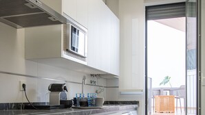Eine moderne Küche mit weißen Schränken, Backofen, Mikrowelle und Waschmaschine.