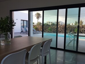Et moderne spiseområde med udsigt til en swimmingpool og en stenvæg.