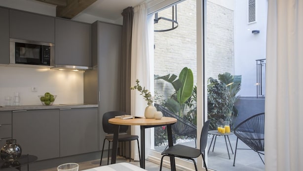 Une cuisine moderne avec des meubles gris, un four à micro-ondes et un coin repas comprenant une table ronde et des chaises.