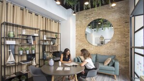 Une salle de réunion moderne avec une table ronde, des chaises noires et un mur en briques agrémenté d’un grand miroir rond.