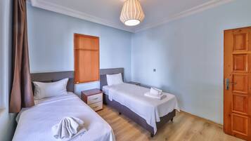 Une chambre d’hôtel avec deux lits, un plancher en bois, un luminaire au plafond et une porte en bois.
