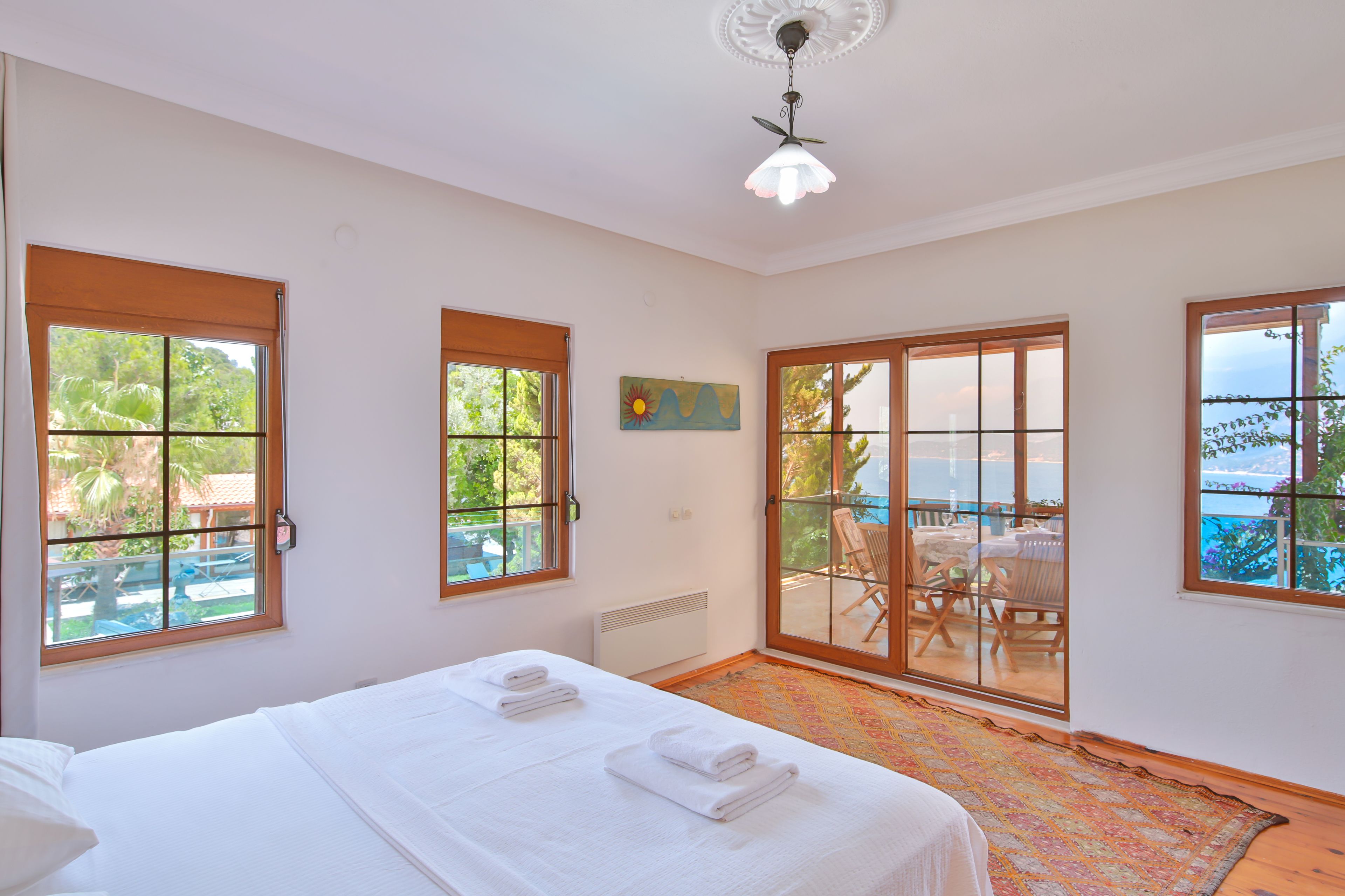 A bedroom with a large bed, two windows, a ceiling fan, and a view of the outdoors.